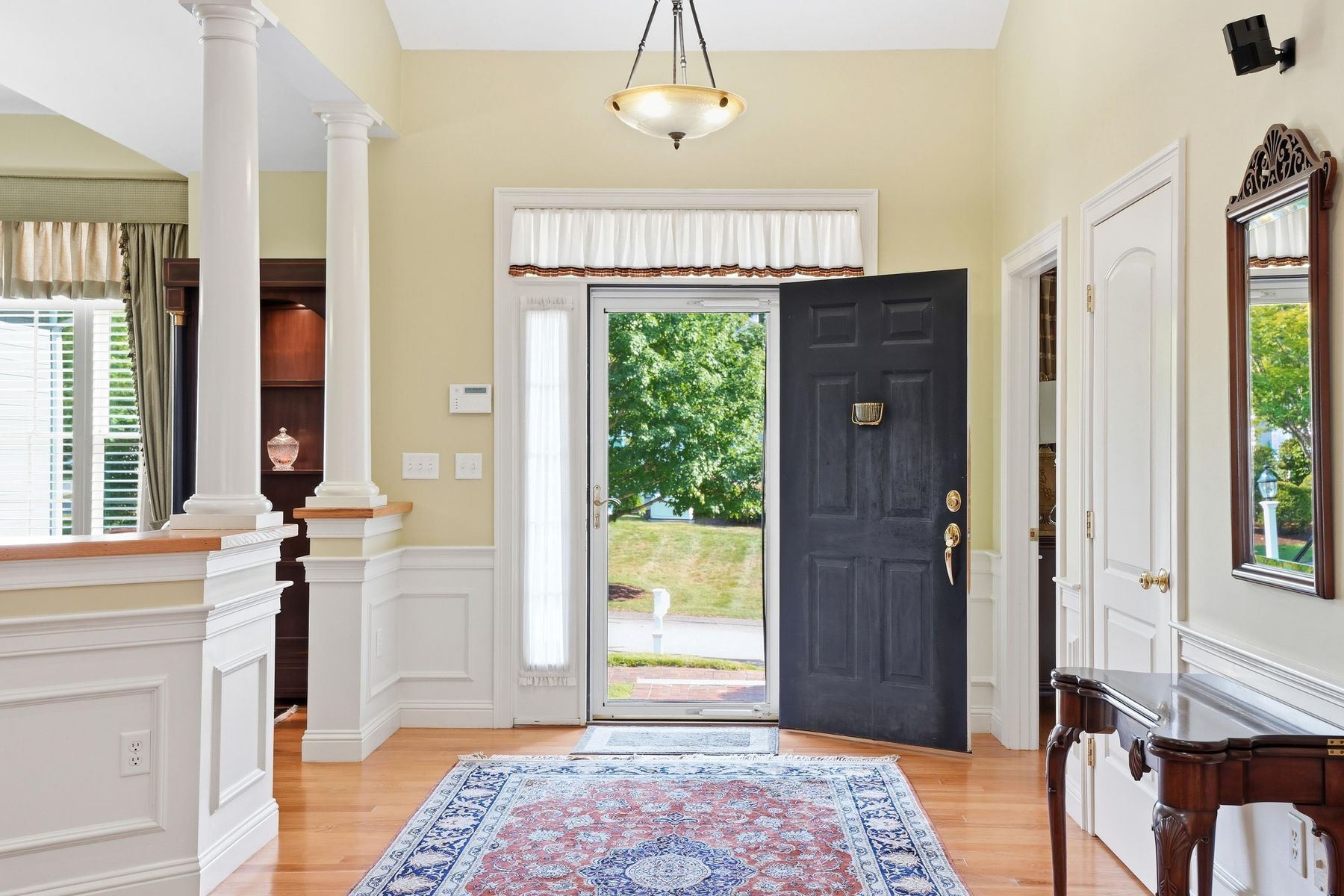 Entry foyer with hardwood floors and columned opening